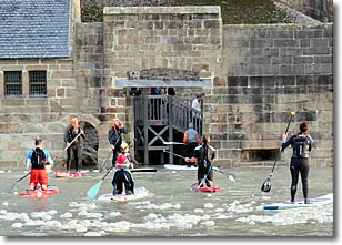 Paddleboards approach Mont Saint-Michel, France at high tide